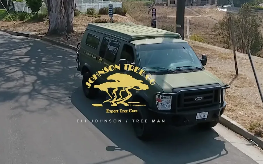 The title card of the Johnson Tree Company film: the company van on a canyon road above the Palisades, under the Johnson Tree Co mark, captioned Eli Johnson / Tree Man.